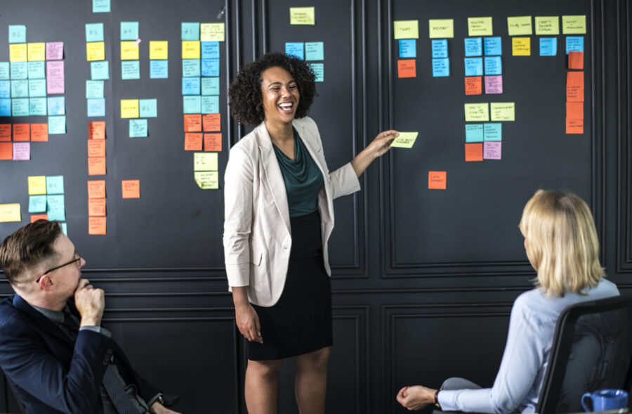 woman laughing at board covered in sticky notes at a meeting