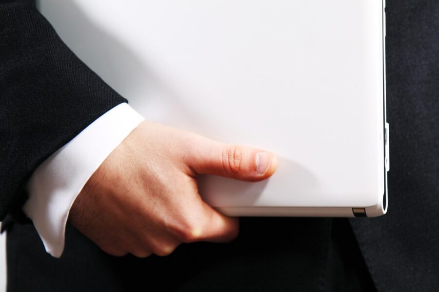 Closeup image a business professional's hand holding a laptop