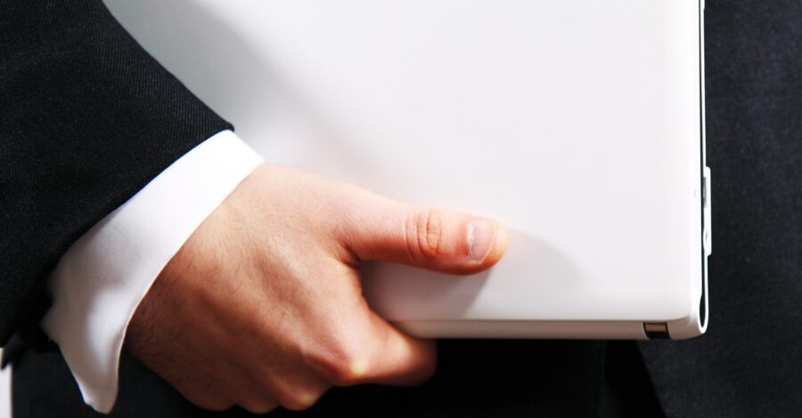 Closeup image a business professional's hand holding a laptop