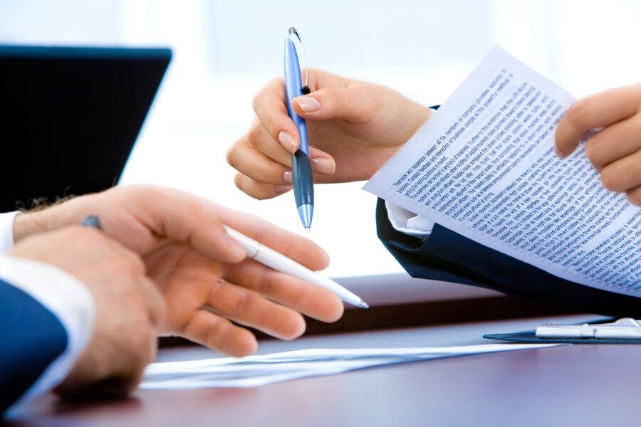 Close view of two hands holding paper and pens in a professional setting